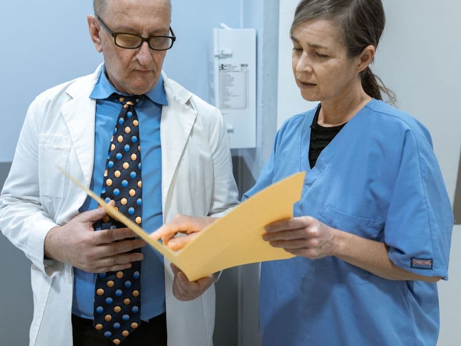 Two clinicians standing together reviewing a patient's file.