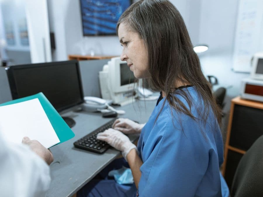 A nurse at a computer working through a patient's records.