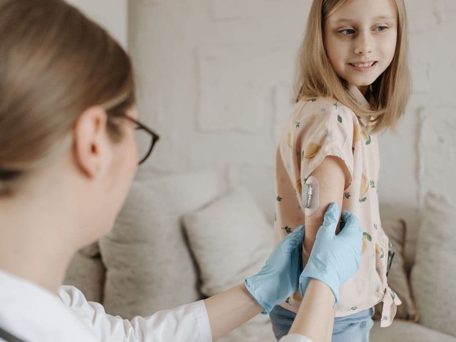 A clinician checking a continuous glucose sensor worn on a patient's upper arm.