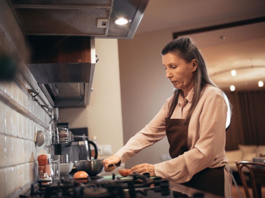 A woman cooking a meal on a hob in a home kitchen.