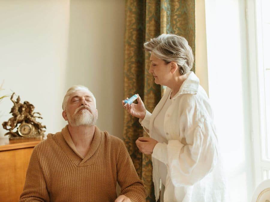 A care worker helping an older man with grooming while he sits in his own home.
