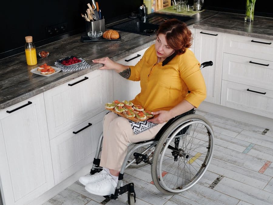 A woman using a wheelchair preparing food independently at her own kitchen counter.