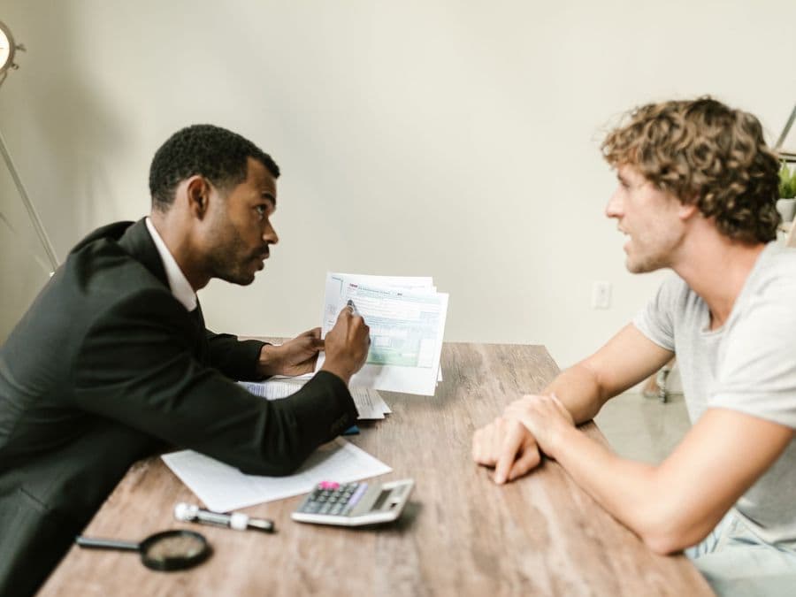 Two men sitting at a table working through documents together.