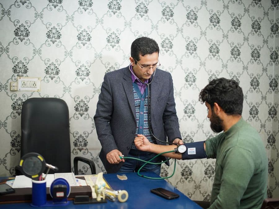 A health worker taking an older man's blood pressure.